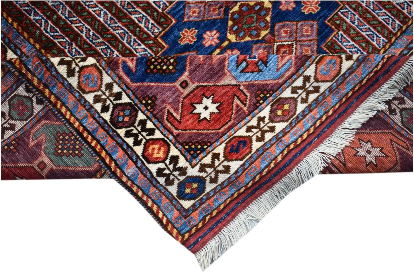 A folded Afghan Herati rug featuring intricate geometric patterns in blue, red, and cream wool.