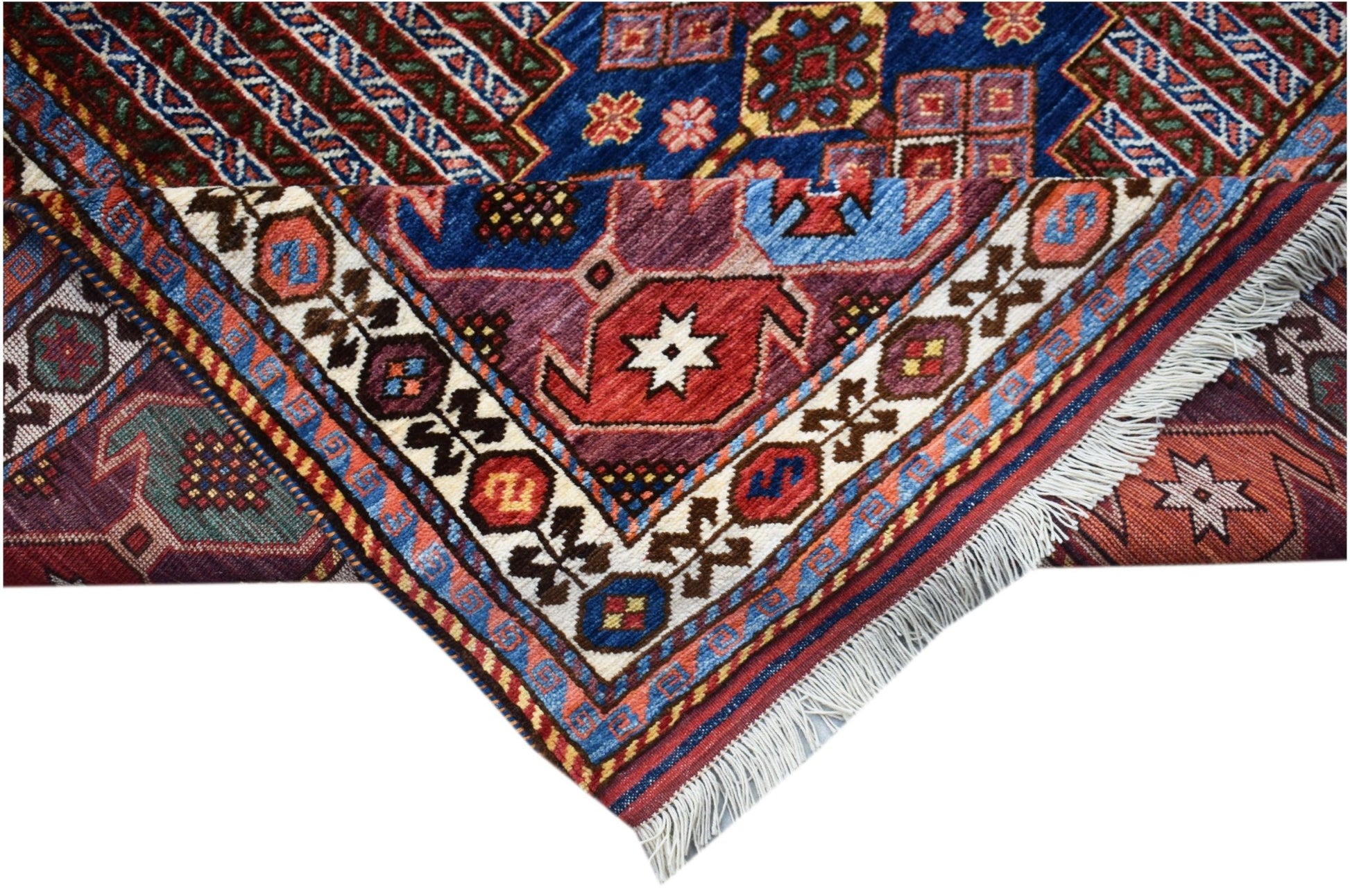 A folded Afghan Herati rug featuring intricate geometric patterns in blue, red, and cream wool.