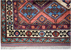 A handwoven Afghan Herati rug featuring geometric diamond patterns in red, blue, and purple wool.