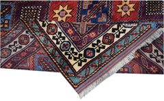 A handwoven Afghan Herati rug featuring intricate geometric patterns in red, blue, and cream tones.