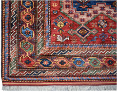 A handmade Afghan Herati rug featuring a red field with geometric patterns and a fringed edge.