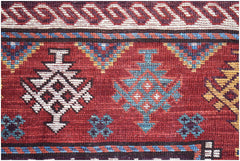 A close-up of a handwoven Afghan Herati rug featuring geometric patterns in red, blue, and cream.