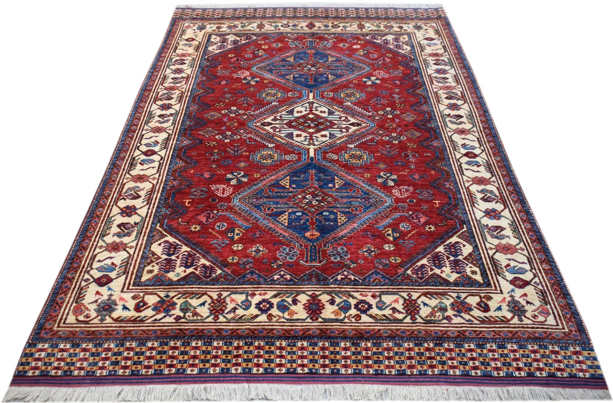 Handwoven Afghan Herati rug featuring a red field with blue diamond medallions and cream borders.