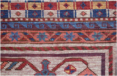 A close-up of an Afghan Herati rug featuring intricate geometric patterns in red, blue, and cream.