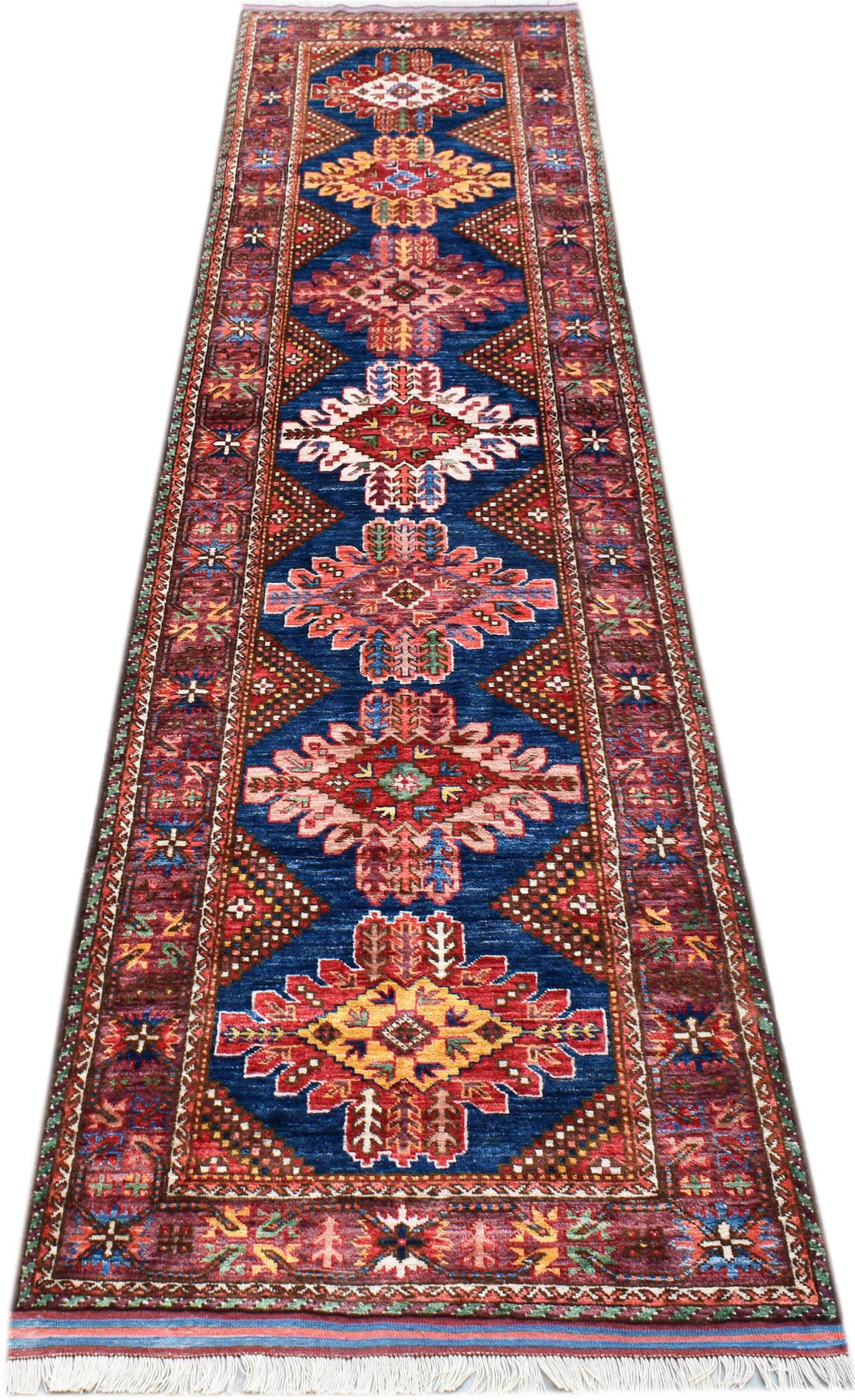 A handmade Afghan Herati runner rug featuring a blue field with repeating geometric floral motifs.