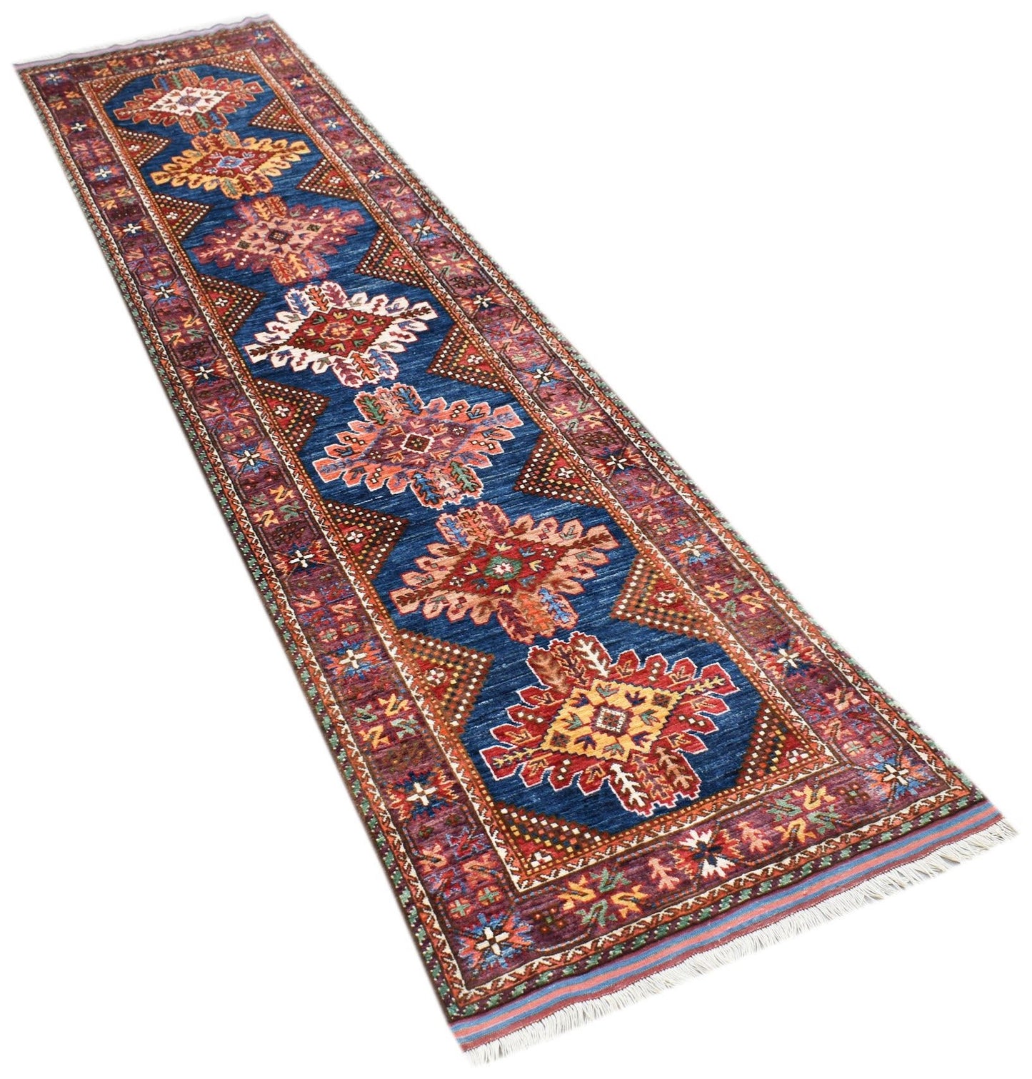 A handwoven Afghan runner rug featuring a blue field with repeating geometric floral medallions.