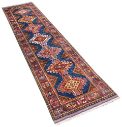 A handwoven Afghan runner rug featuring a blue field with repeating geometric floral medallions.