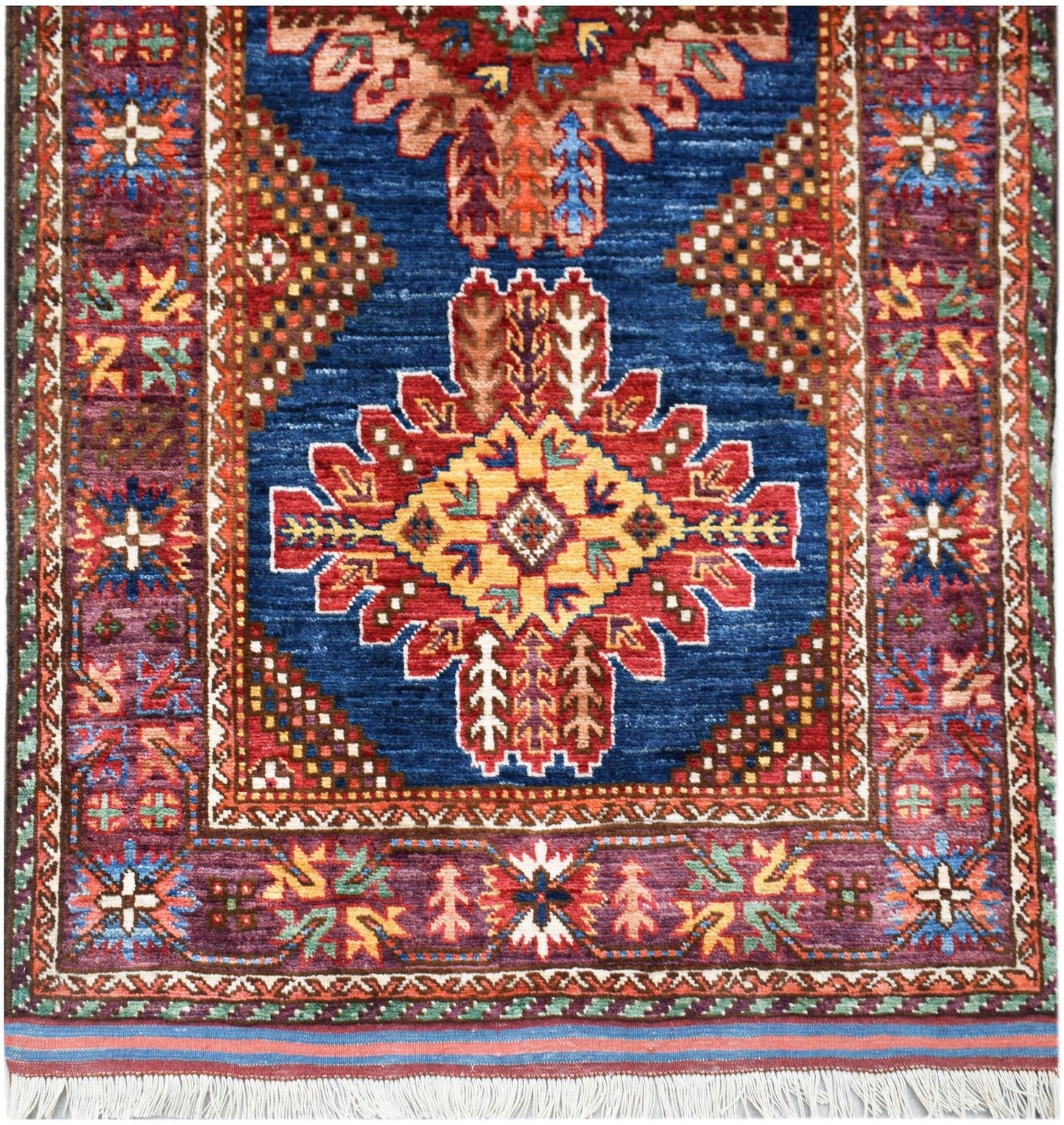 Handwoven Afghan Herati runner featuring a central geometric medallion on a deep blue field.