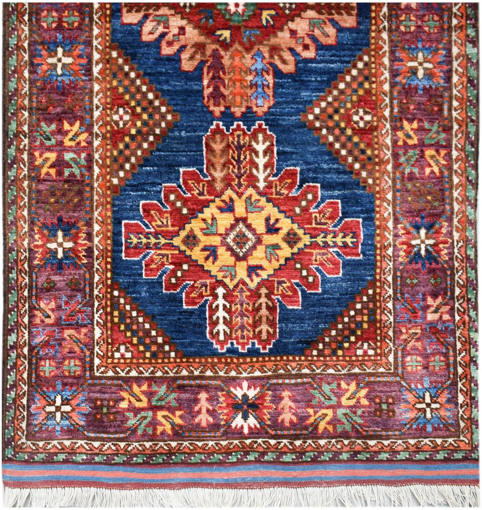 Handwoven Afghan Herati runner featuring a central geometric medallion on a deep blue field.