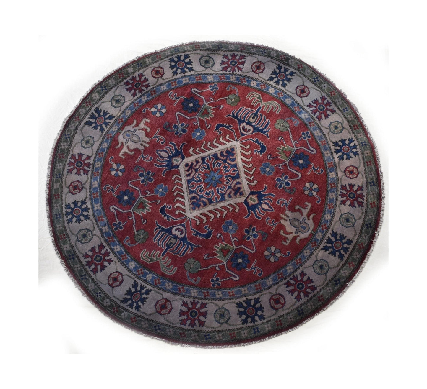 A round, handmade Afghan Kazakh rug featuring a red center with geometric patterns and a grey border.
