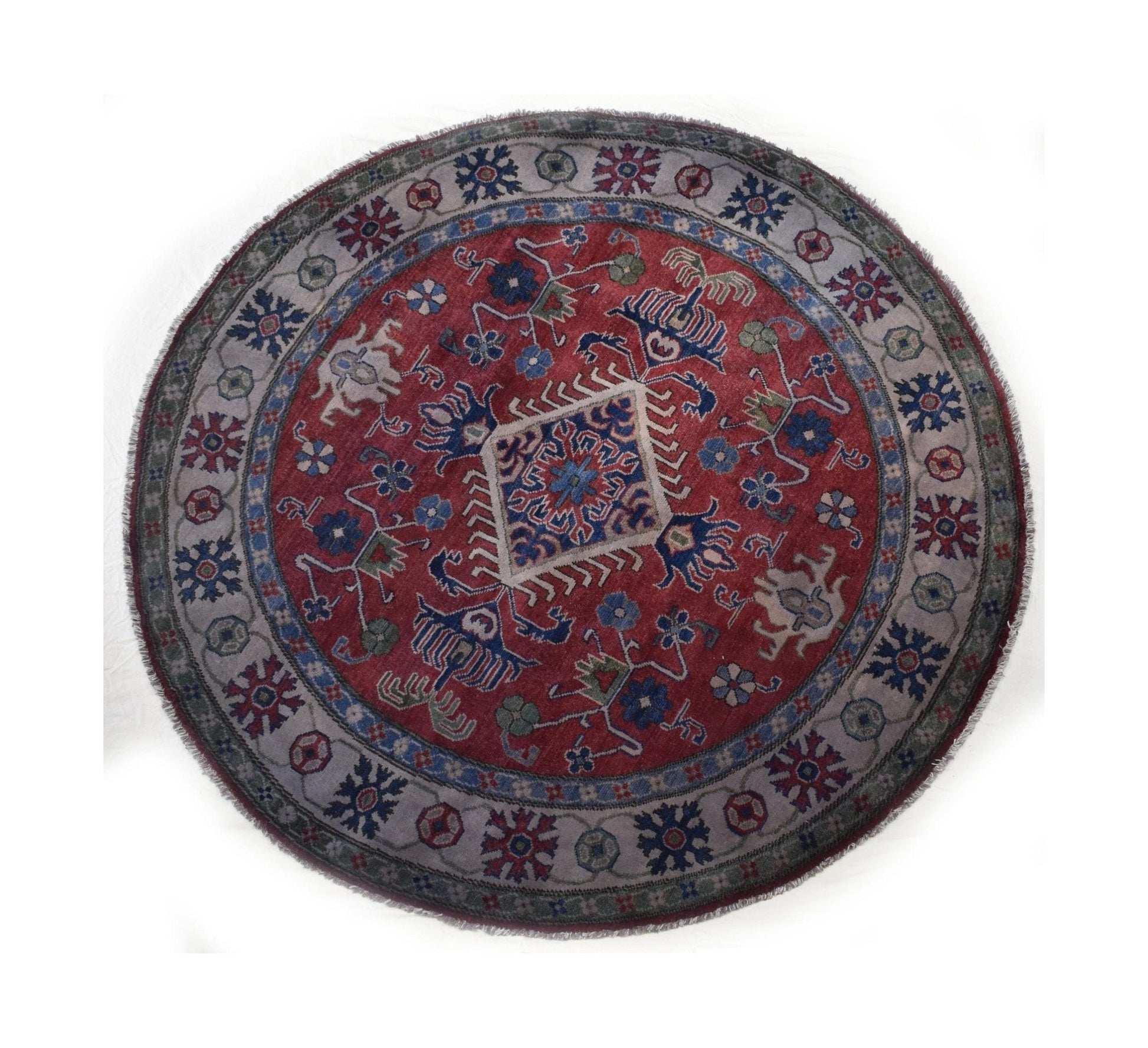 A round, handmade Afghan Kazakh rug featuring a red center with geometric patterns and a grey border.