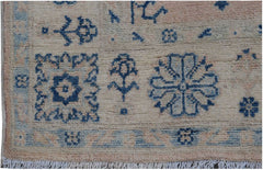 Handmade Afghan Kazakh rug featuring blue geometric and floral motifs on a beige wool background.