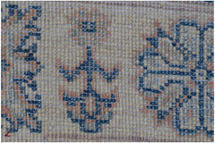 A close-up of an Afghan Kazakh rug featuring traditional blue and peach geometric floral patterns.