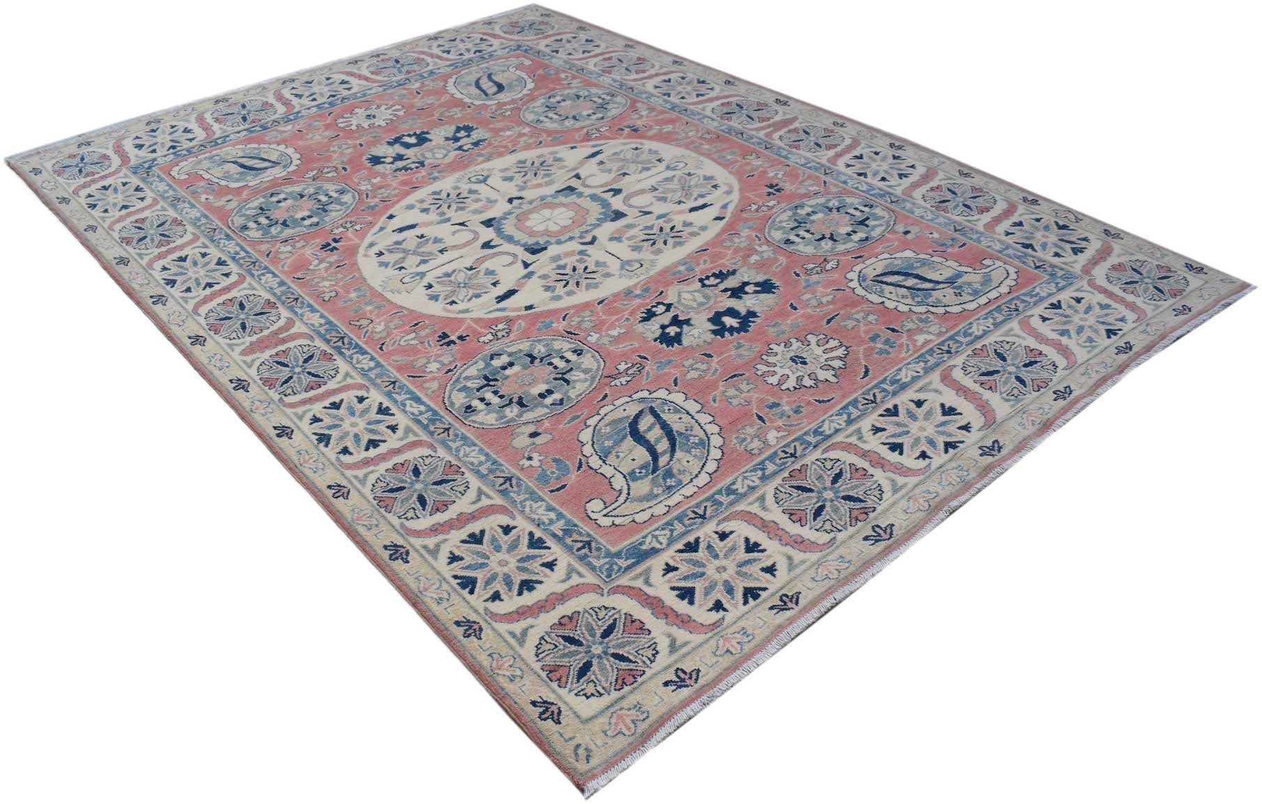 A handmade Afghan Kazakh rug featuring traditional blue and cream floral motifs on a pink field.