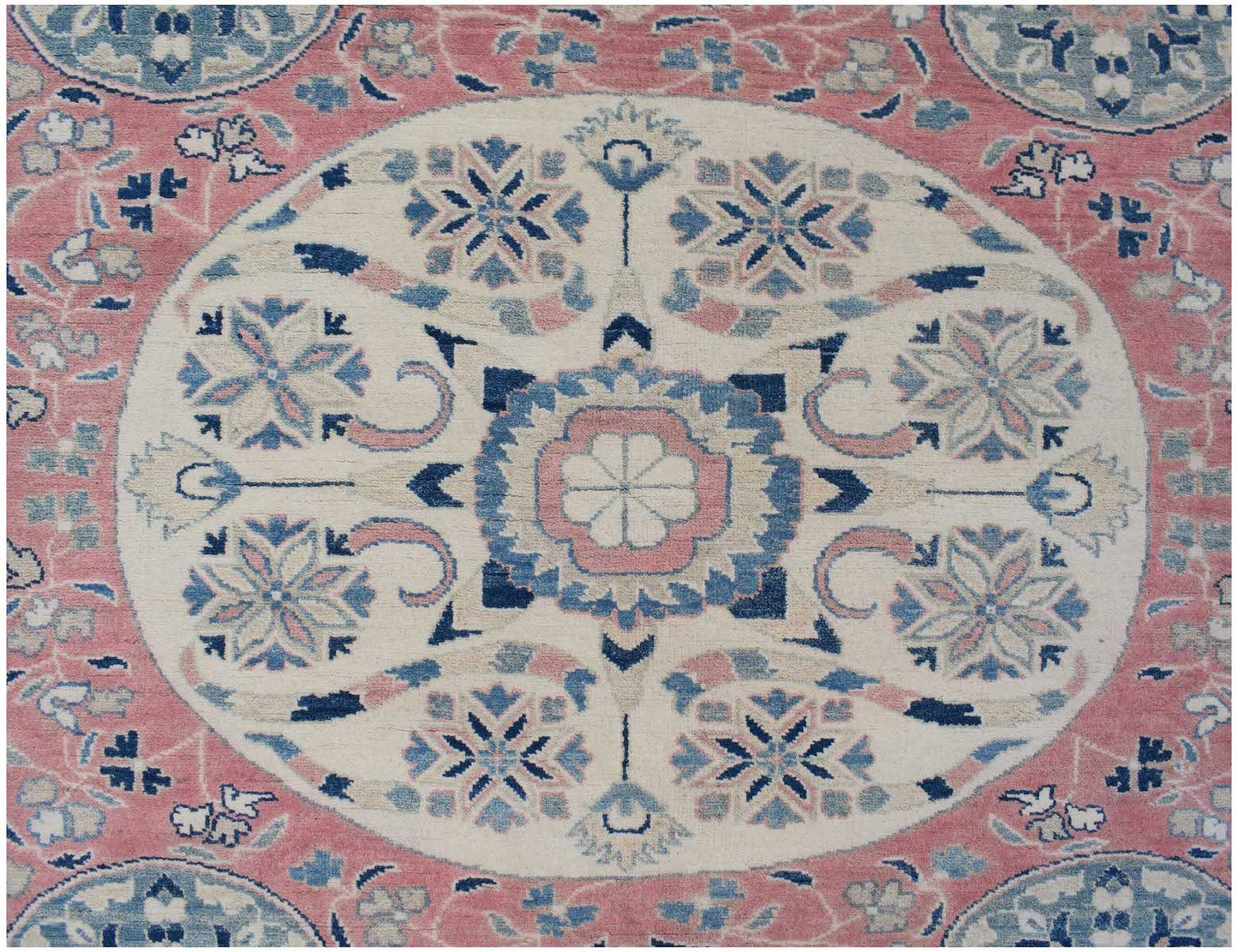Handmade Afghan Kazakh rug featuring a central floral medallion in pink, blue, and cream tones.