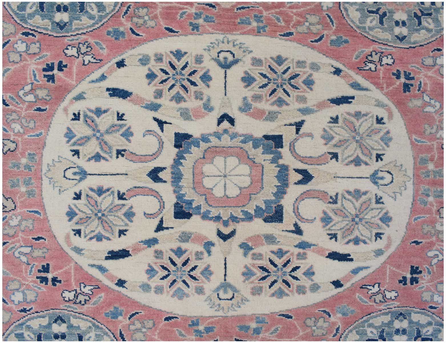 Handmade Afghan Kazakh rug featuring a central floral medallion in pink, blue, and cream tones.