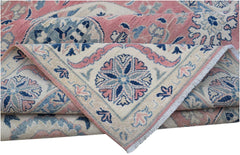 A folded Afghan Kazakh rug featuring traditional floral motifs in shades of pink, blue, and cream.