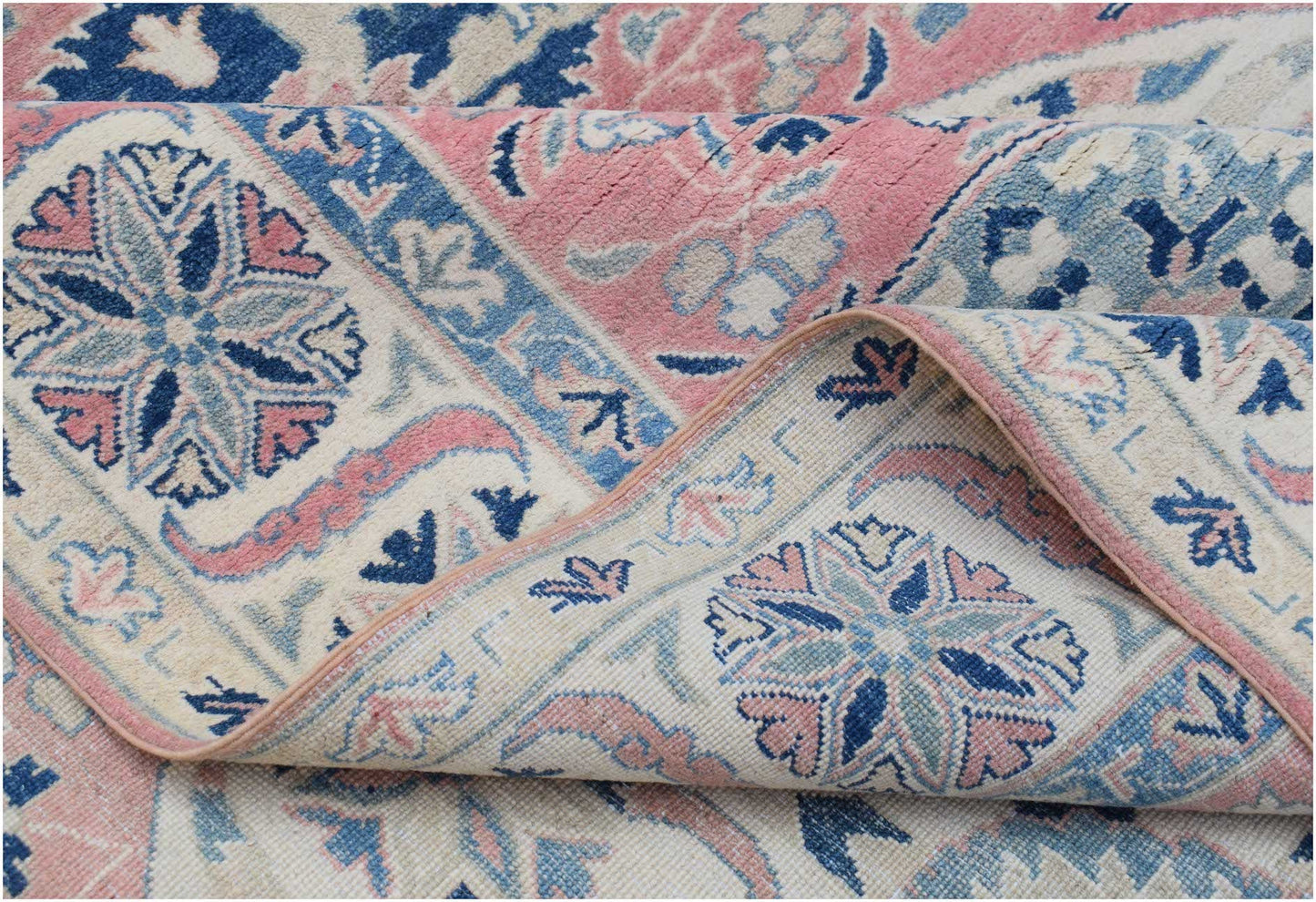 A handmade Afghan Kazakh rug featuring traditional floral motifs in shades of pink, blue, and cream.