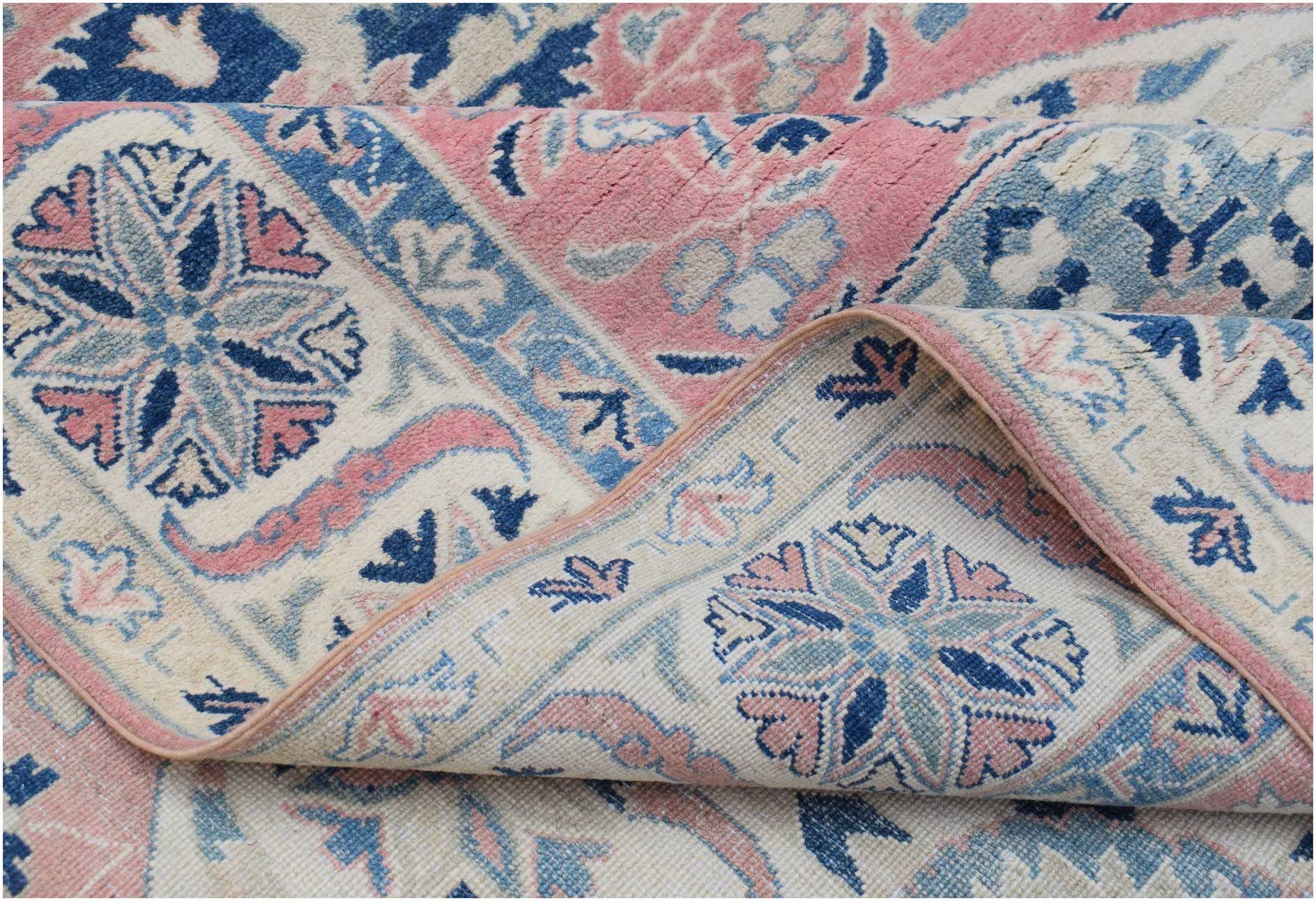 A handmade Afghan Kazakh rug featuring traditional floral motifs in shades of pink, blue, and cream.