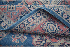 A handmade Afghan Kazakh rug featuring traditional geometric motifs in blue, pink, and cream.