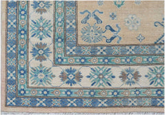 A handmade Afghan Kazakh rug featuring a beige field with blue and grey floral geometric patterns.