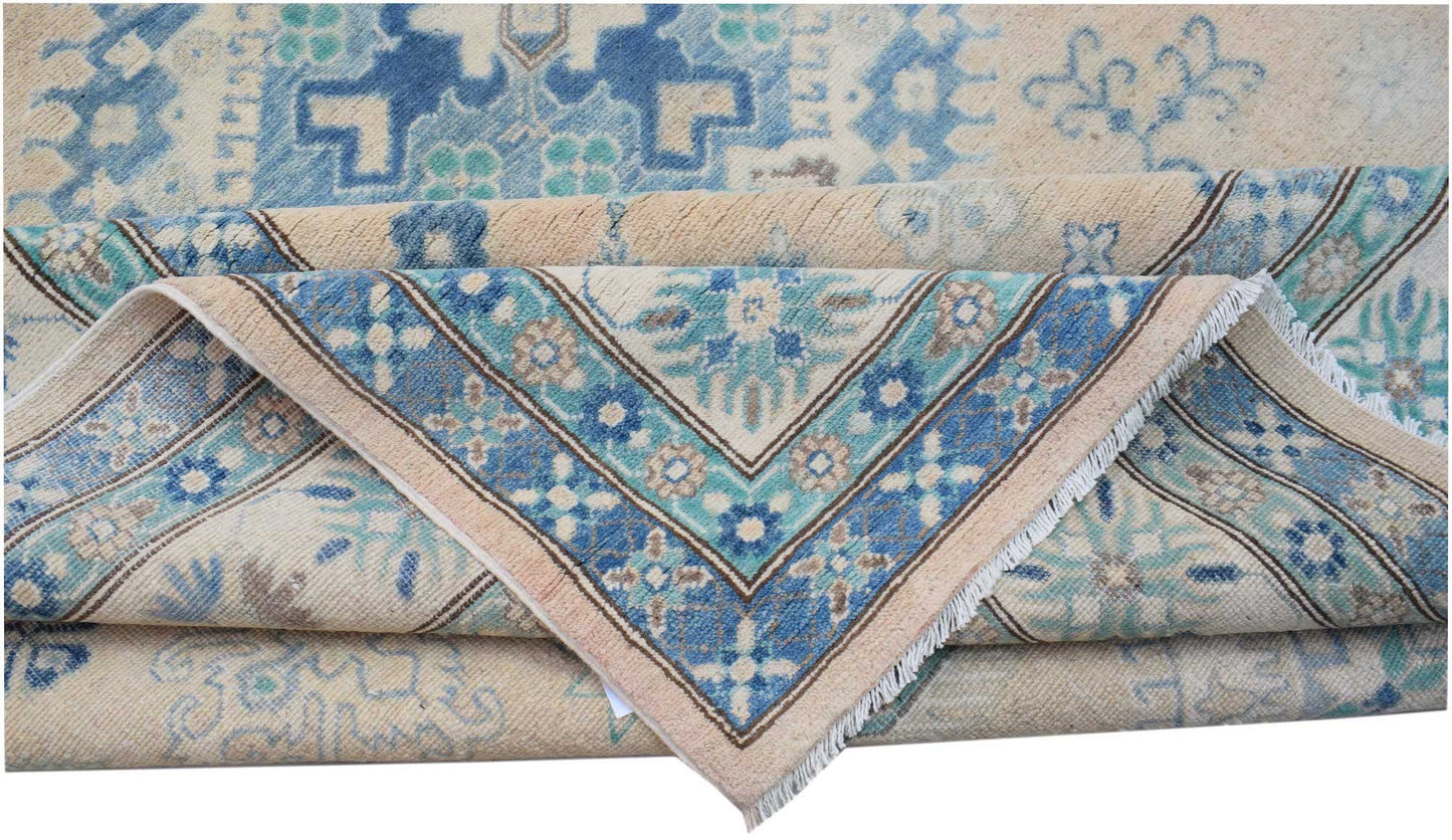 A handmade Afghan Kazakh rug featuring a beige background with blue and teal floral patterns.