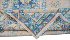A handmade Afghan Kazakh rug featuring a beige background with blue and teal floral patterns.