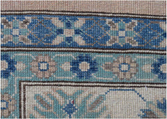 A close-up of an Afghan Kazakh rug featuring intricate geometric floral patterns in blue, beige, and grey.