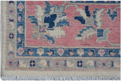 A handmade Afghan Kazakh rug featuring traditional floral motifs in blue and pink on a wool pile.