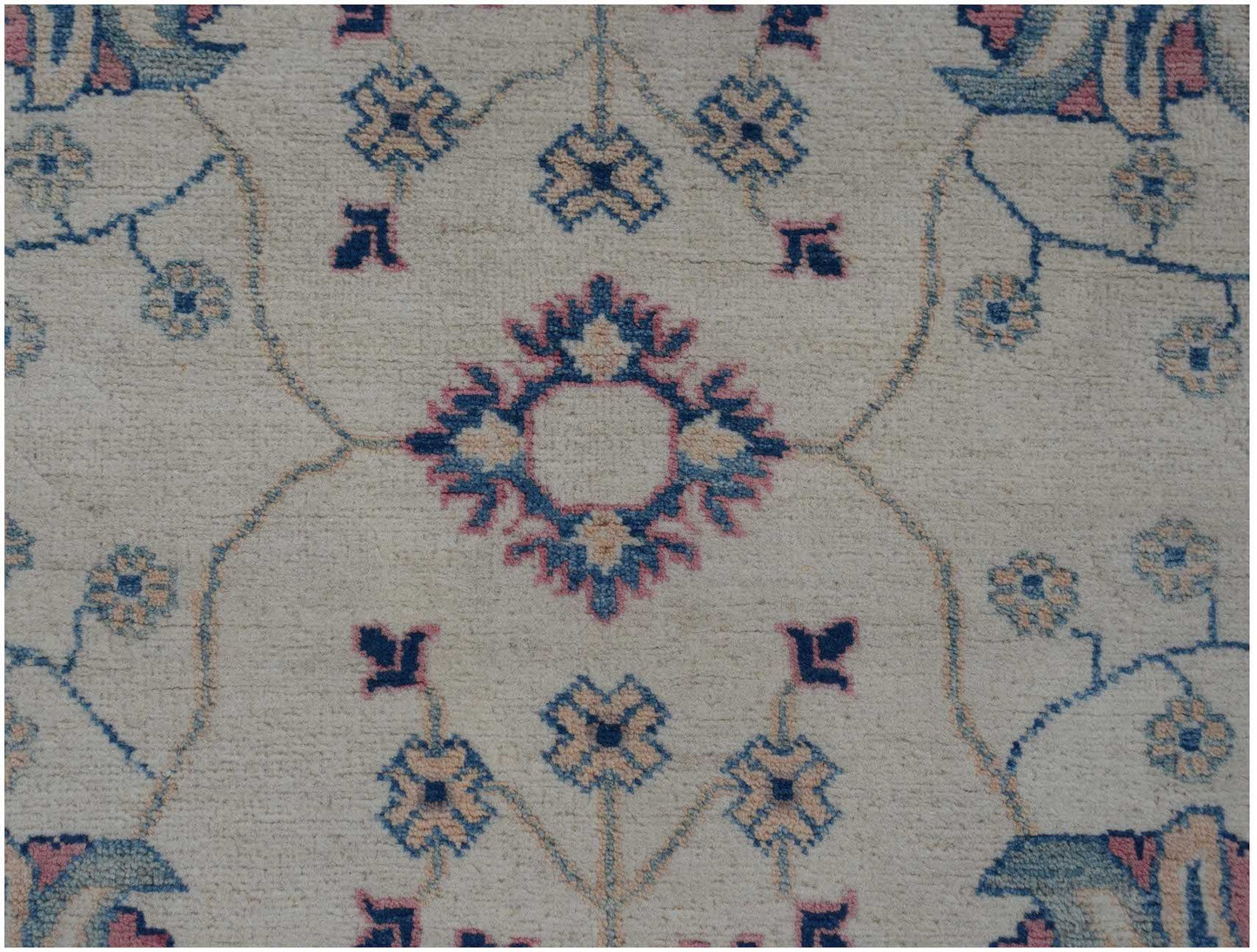 An Afghan Kazakh rug featuring a cream field with traditional blue and pink floral motifs.
