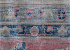 A close-up of an Afghan Kazakh rug featuring traditional geometric patterns in blue and pink wool.