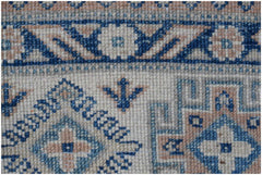 A close-up of a handmade Afghan Kazakh rug featuring geometric blue and beige patterns.