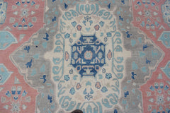 Handmade Afghan Kazakh rug featuring a geometric central medallion in blue, pink, and grey tones.
