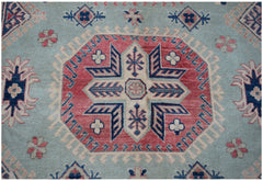 A handmade Afghan Kazakh rug featuring a central geometric medallion on a light blue field.