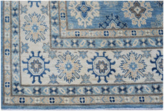 An Afghan Kazakh rug featuring a geometric floral pattern in shades of blue, beige, and grey.