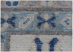 A close-up view of a handmade Afghan Kazakh rug featuring geometric blue patterns on a beige base.