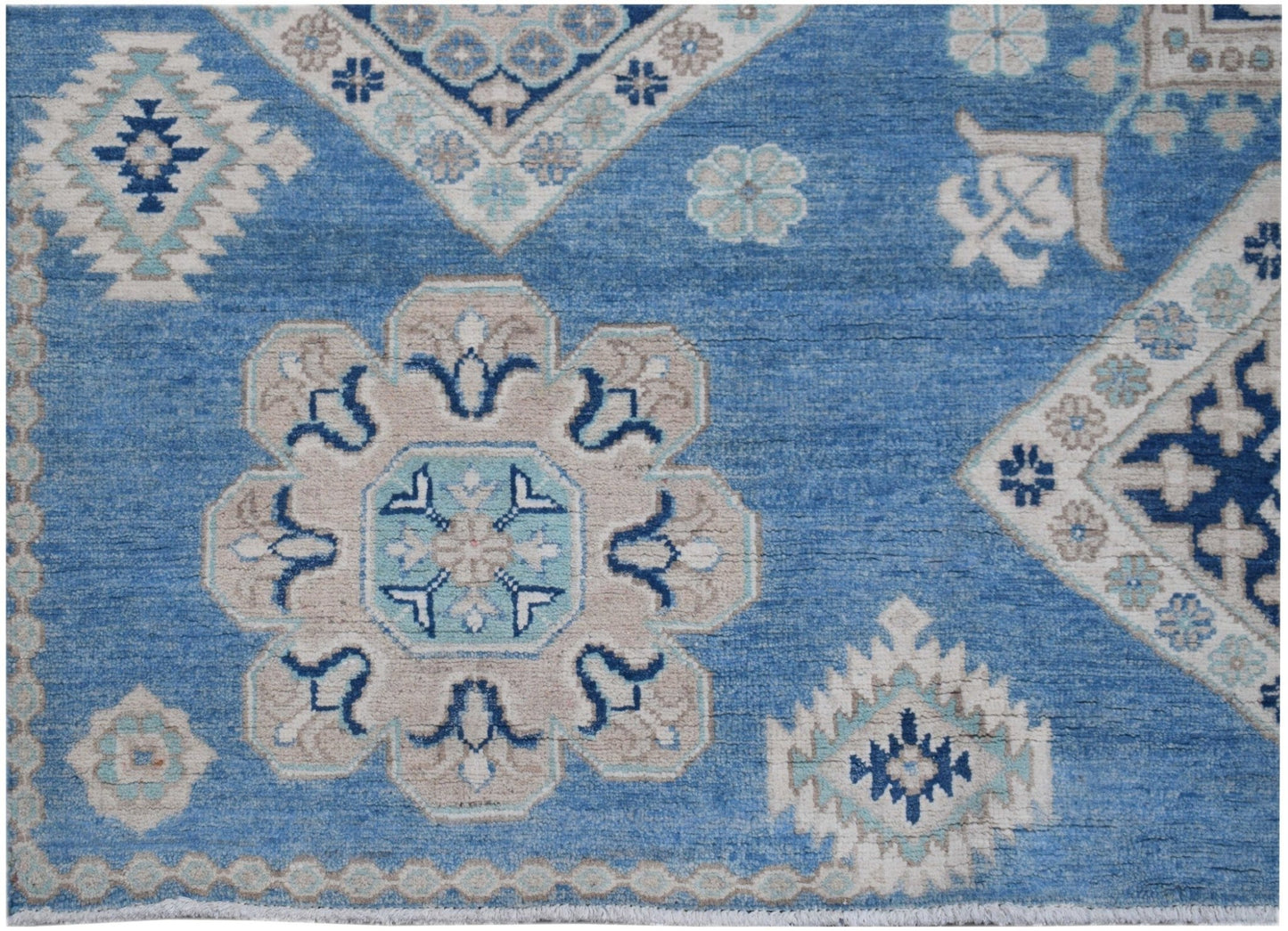 Handmade Afghan Kazakh rug featuring a blue field with beige and light blue geometric motifs.