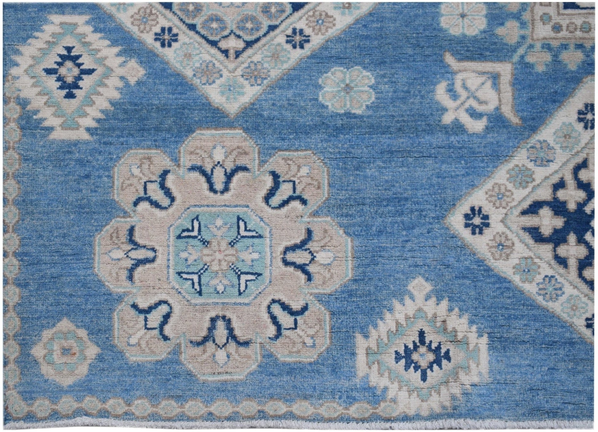 Handmade Afghan Kazakh rug featuring a blue field with beige and light blue geometric motifs.