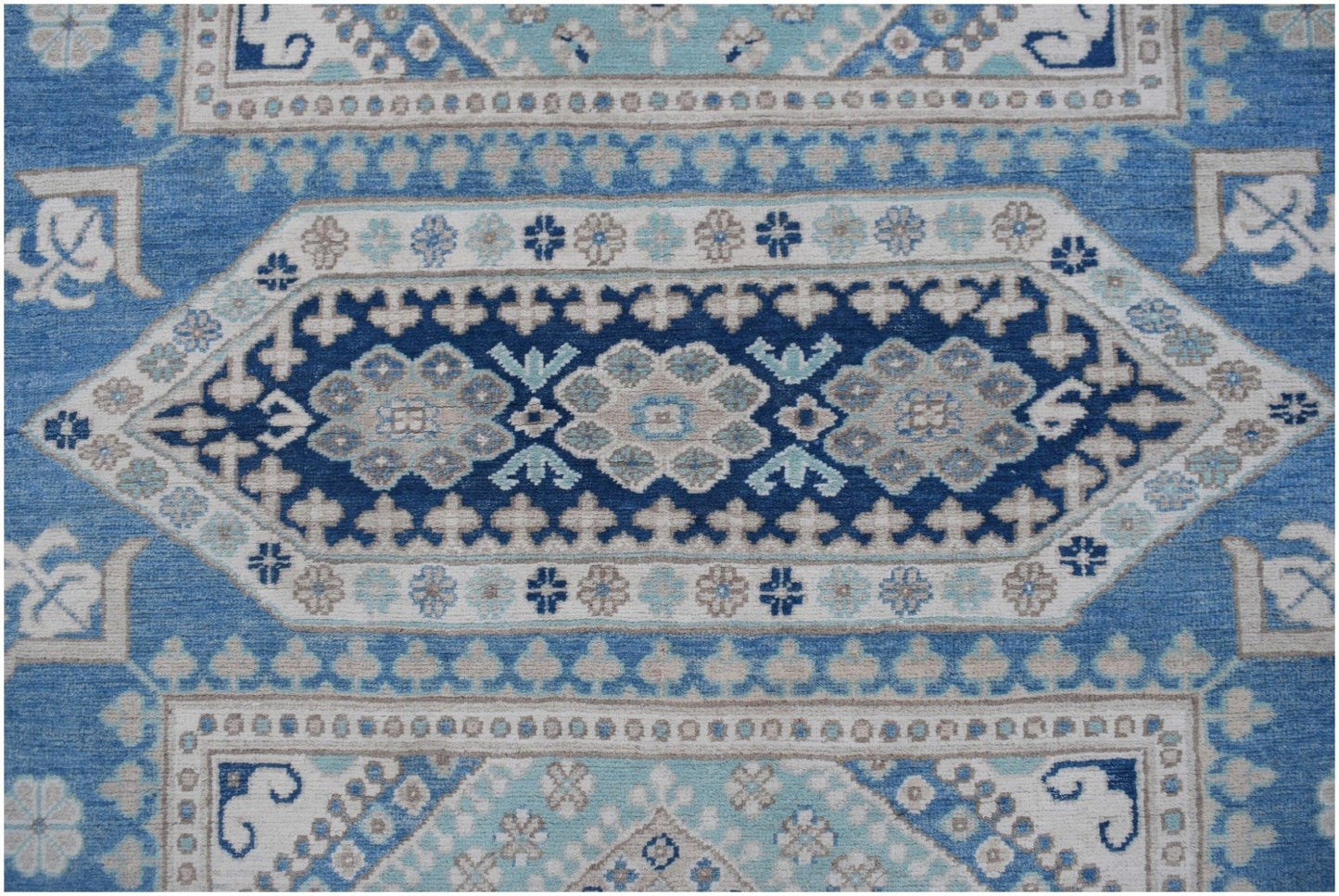 Handmade Afghan Kazakh rug featuring a geometric medallion pattern in shades of blue and beige.