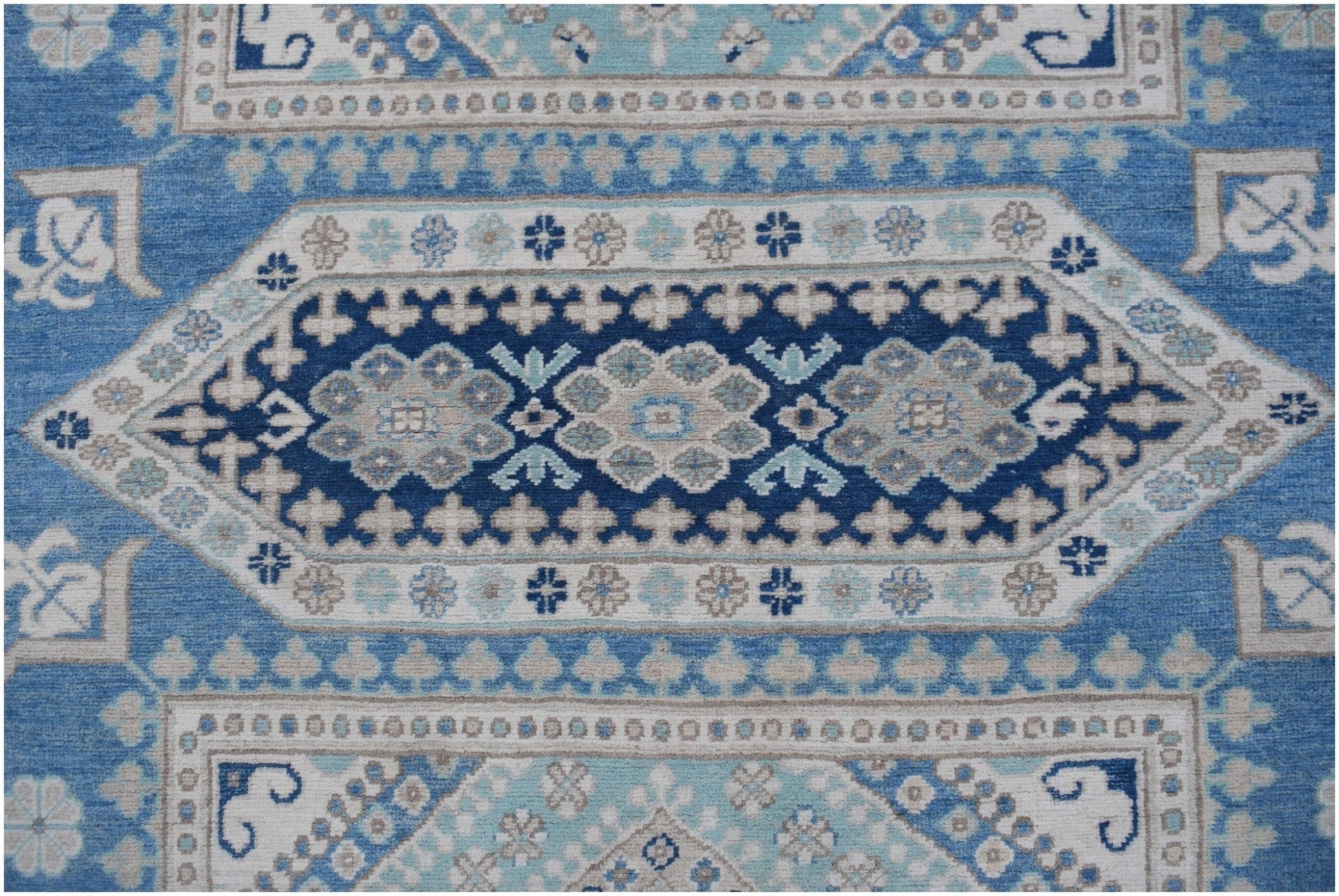 Handmade Afghan Kazakh rug featuring a geometric medallion pattern in shades of blue and beige.