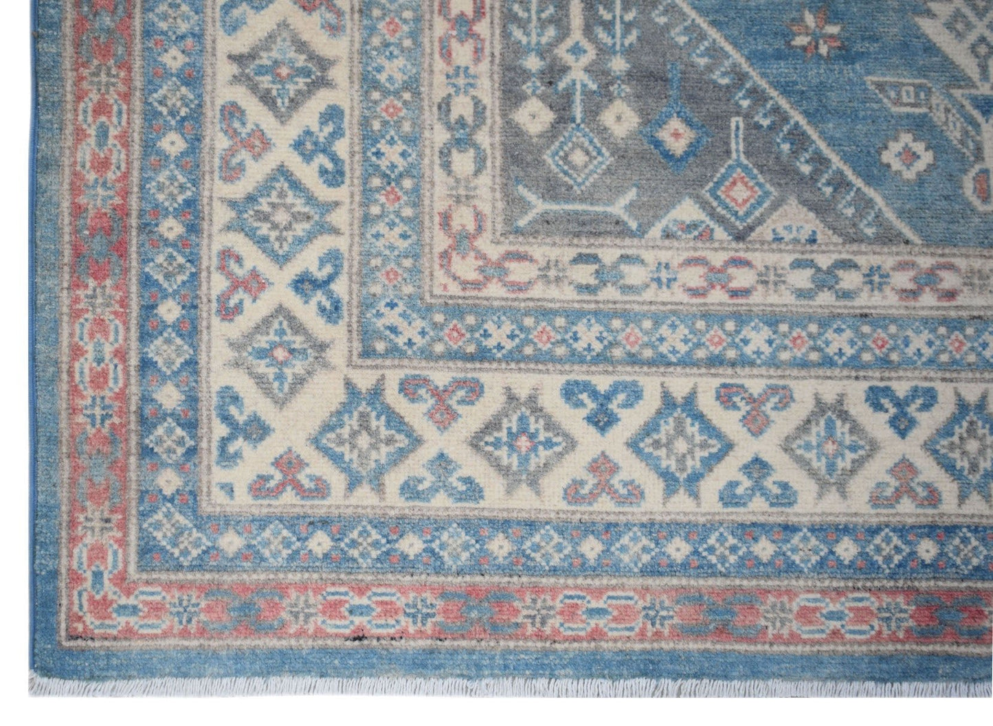 A handmade Afghan Kazakh rug featuring traditional geometric patterns in blue, cream, and red.