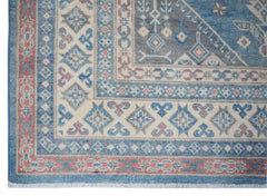 A handmade Afghan Kazakh rug featuring traditional geometric patterns in blue, cream, and red.