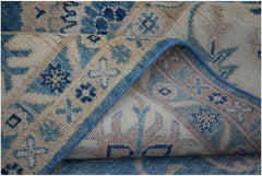 A folded Afghan Kazakh wool rug featuring traditional geometric patterns in blue and beige.
