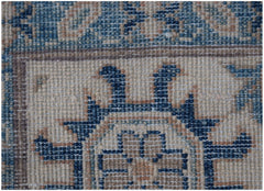 A close-up of a handmade Afghan Kazakh rug featuring traditional blue and beige geometric patterns.