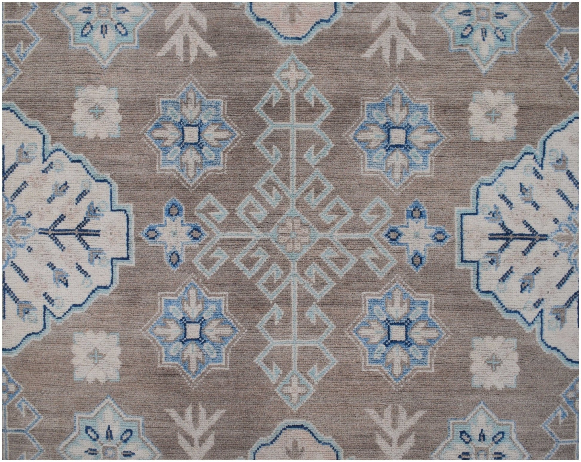 Handmade Afghan Kazakh rug featuring a geometric pattern in shades of beige, blue, and grey.