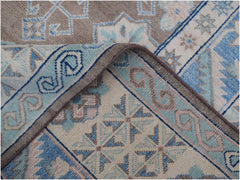 A handmade Afghan Kazakh rug featuring a geometric pattern in shades of beige, blue, and grey.