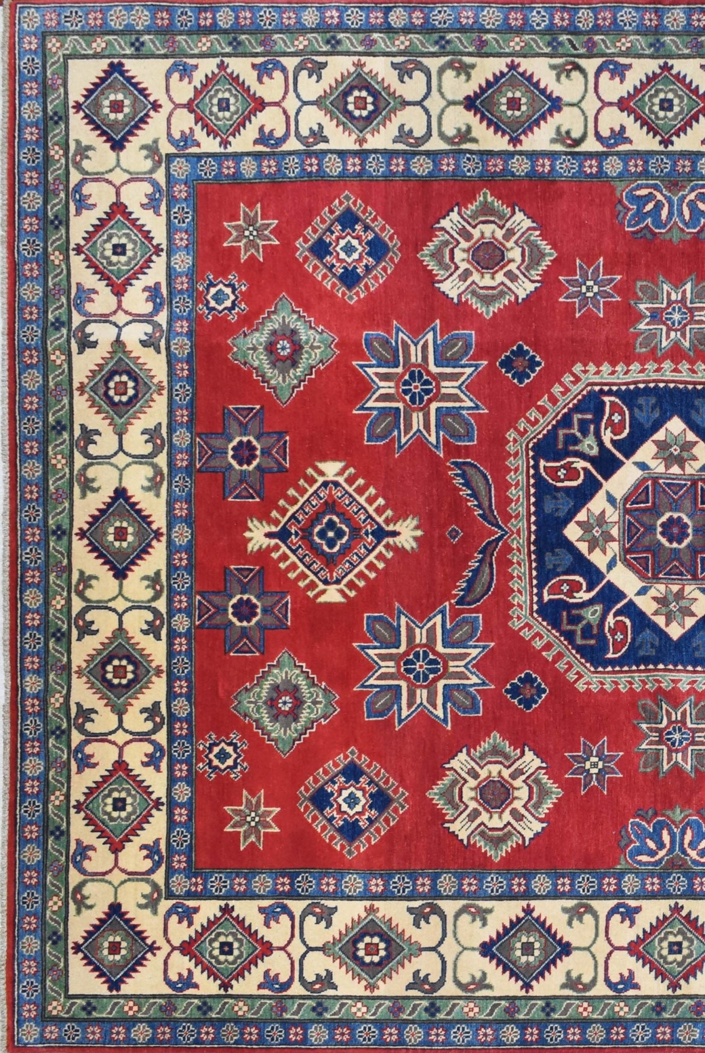 Handmade Afghan Kazakh rug featuring geometric star and diamond motifs on a red wool field.