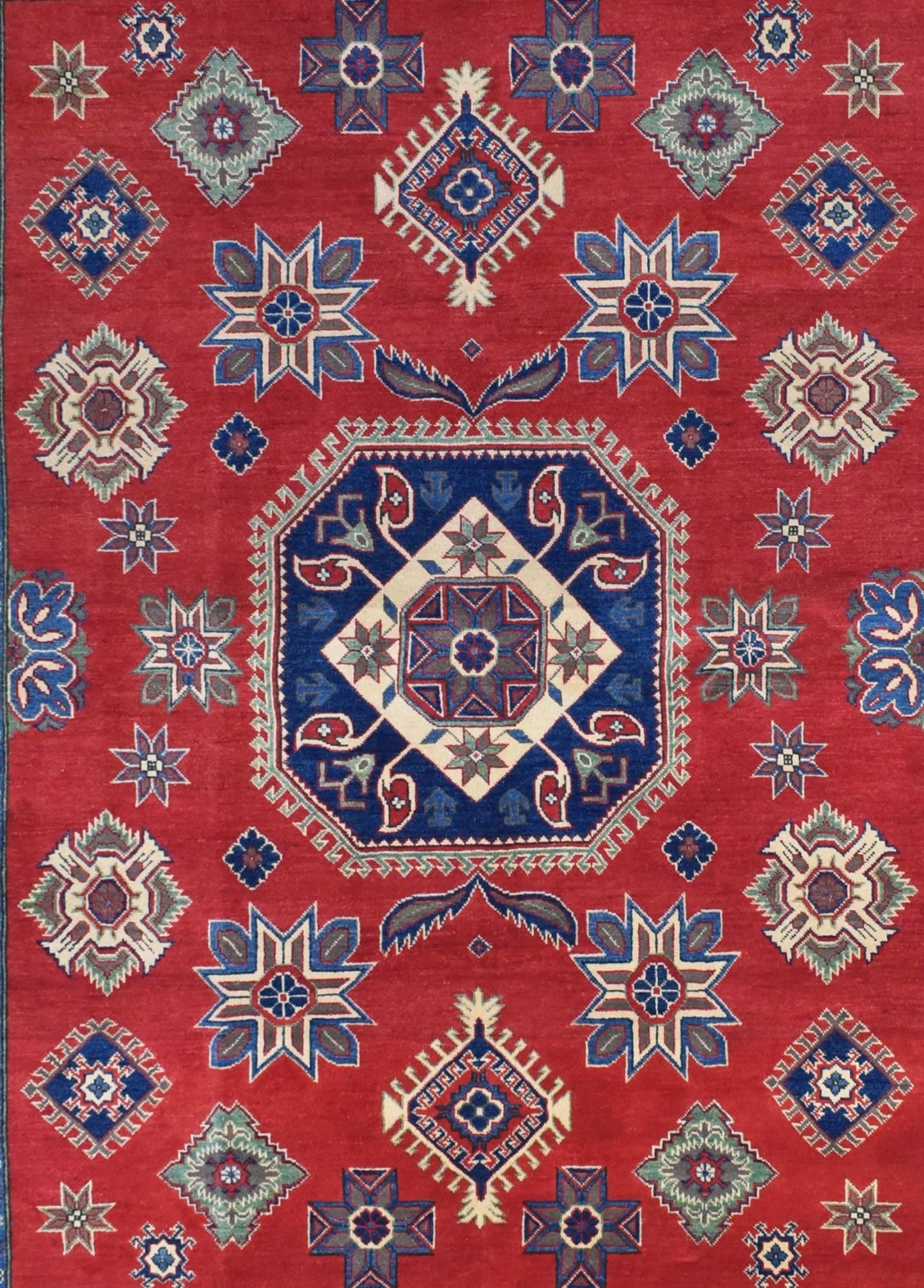 Handmade Afghan Kazakh rug featuring a geometric medallion pattern on a red wool background.