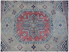 Handmade Afghan Kazakh rug featuring a central geometric medallion in red, blue, and cream wool.