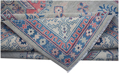 A handmade Afghan Kazakh rug featuring traditional geometric motifs in blue, pink, and cream wool.